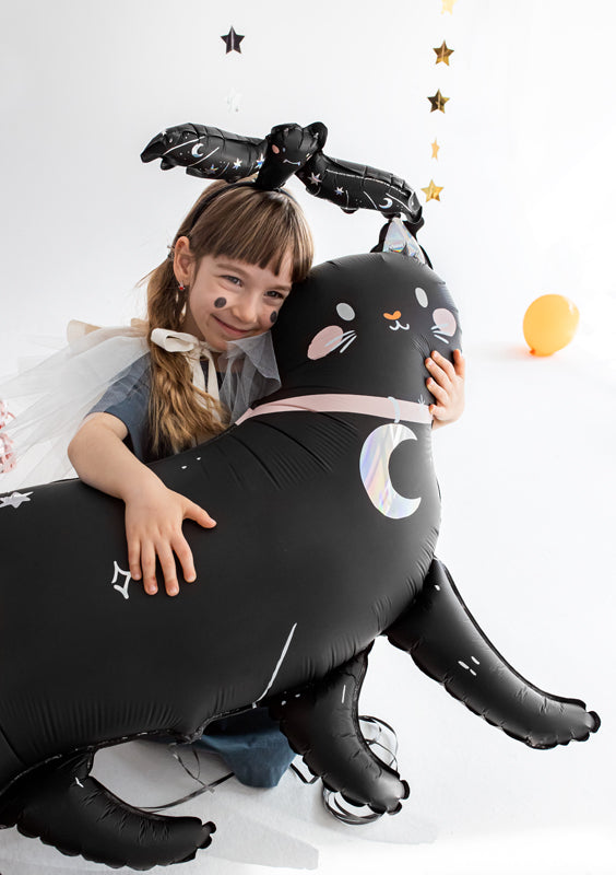 Child playing with black cat foil balloon