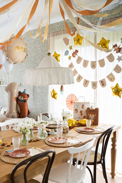 Dining room with a wooden table set for a meal, decorated with balloons and streamers.
