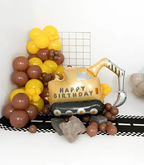 Balloon construction vehicle with 'Happy Birthday' text  surrounded by yellow and brown balloons.