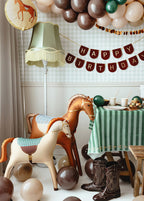 Children's birthday party setup with balloon horses, balloons, and a 'Happy Birthday' banner.
