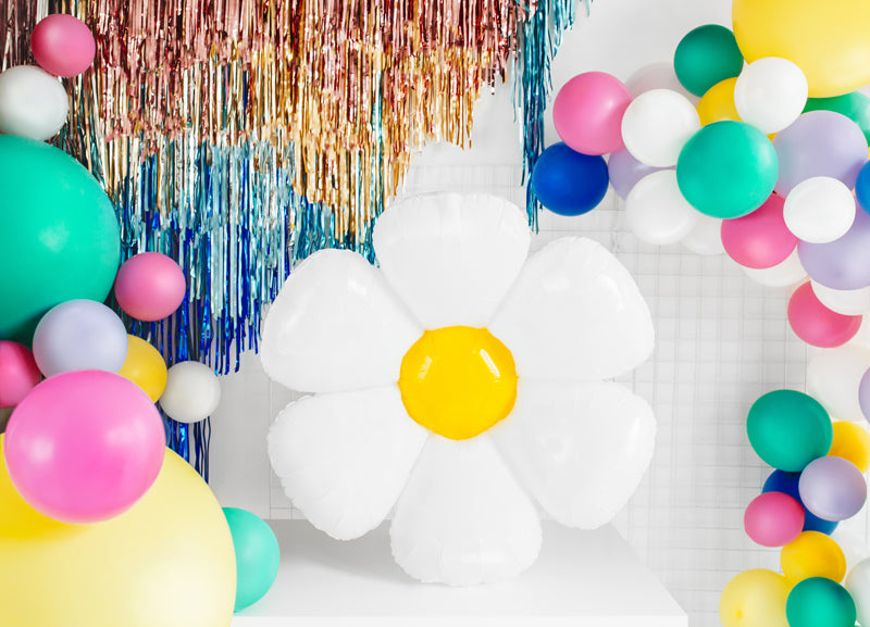Colorful balloon arch with flower balloon and tinsel decorations on a white background