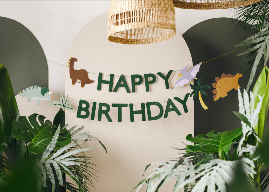 Dino Party Happy Birthday banner styled with dinosaur themed party decorations