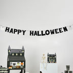 Halloween-themed decorations including a 'Happy Halloween' banner, Cake stand, and a skeleton on a white wall.