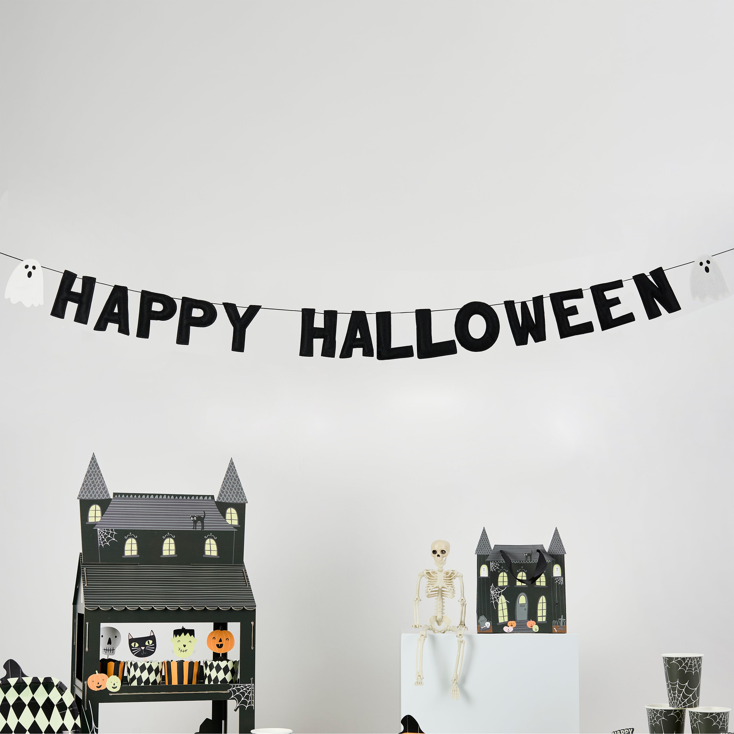 Halloween-themed decorations including a 'Happy Halloween' banner, Cake stand, and a skeleton on a white wall.