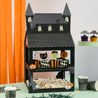 Halloween-themed treat stand with black house design, popcorn, and small pumpkins on a table.