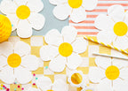 White paper flowers with yellow centers on a colorful checkered background