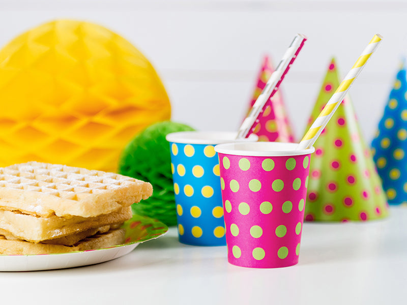 Yellow striped paper straws styled in party drinks on a colourful party table