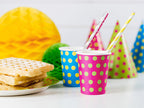 Yellow striped paper straws styled in party drinks on a colourful party table