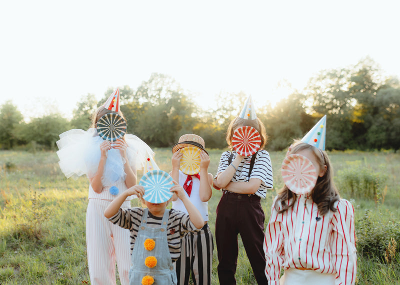 Big Top Circus striped plates styled at carnival themed party table with children holding them over faces