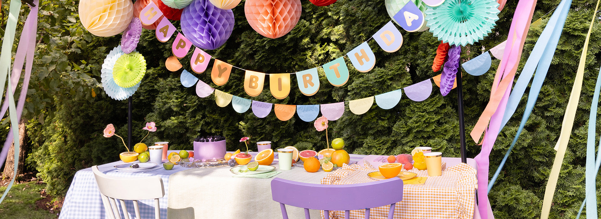 Decorated outdoor table with colorful paper decorations and a banner.